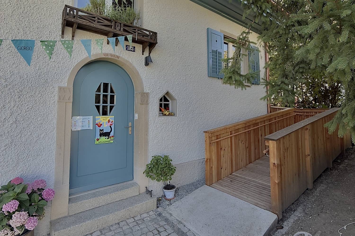 &Uuml;ber einem blauen Eingangstor zu einem Haus h&auml;ngen Wimpel in verschiedenen Blaut&ouml;nen